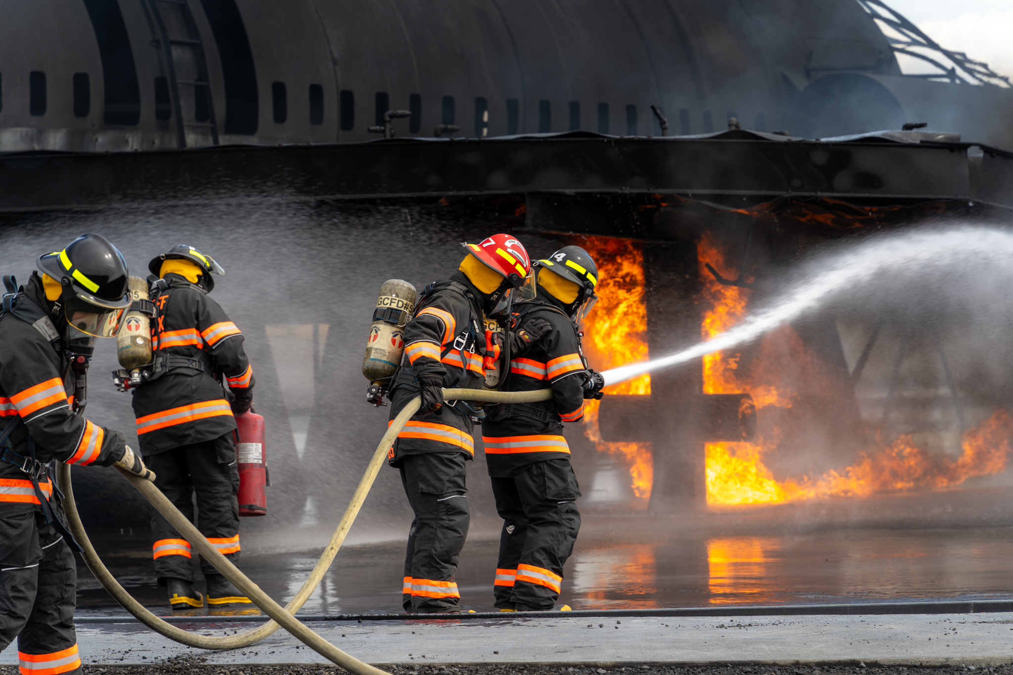 Four firefighters spraying water on burning plane