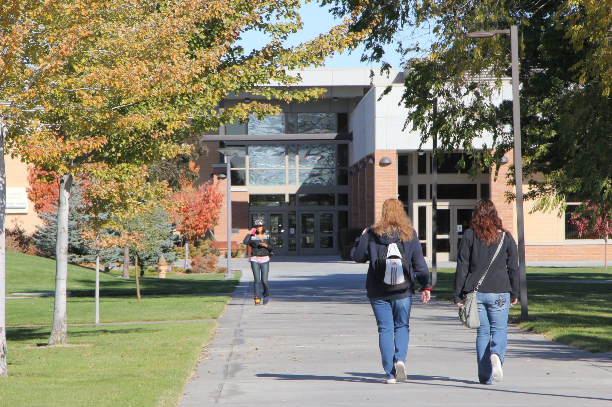 two students walking away from camera towards building